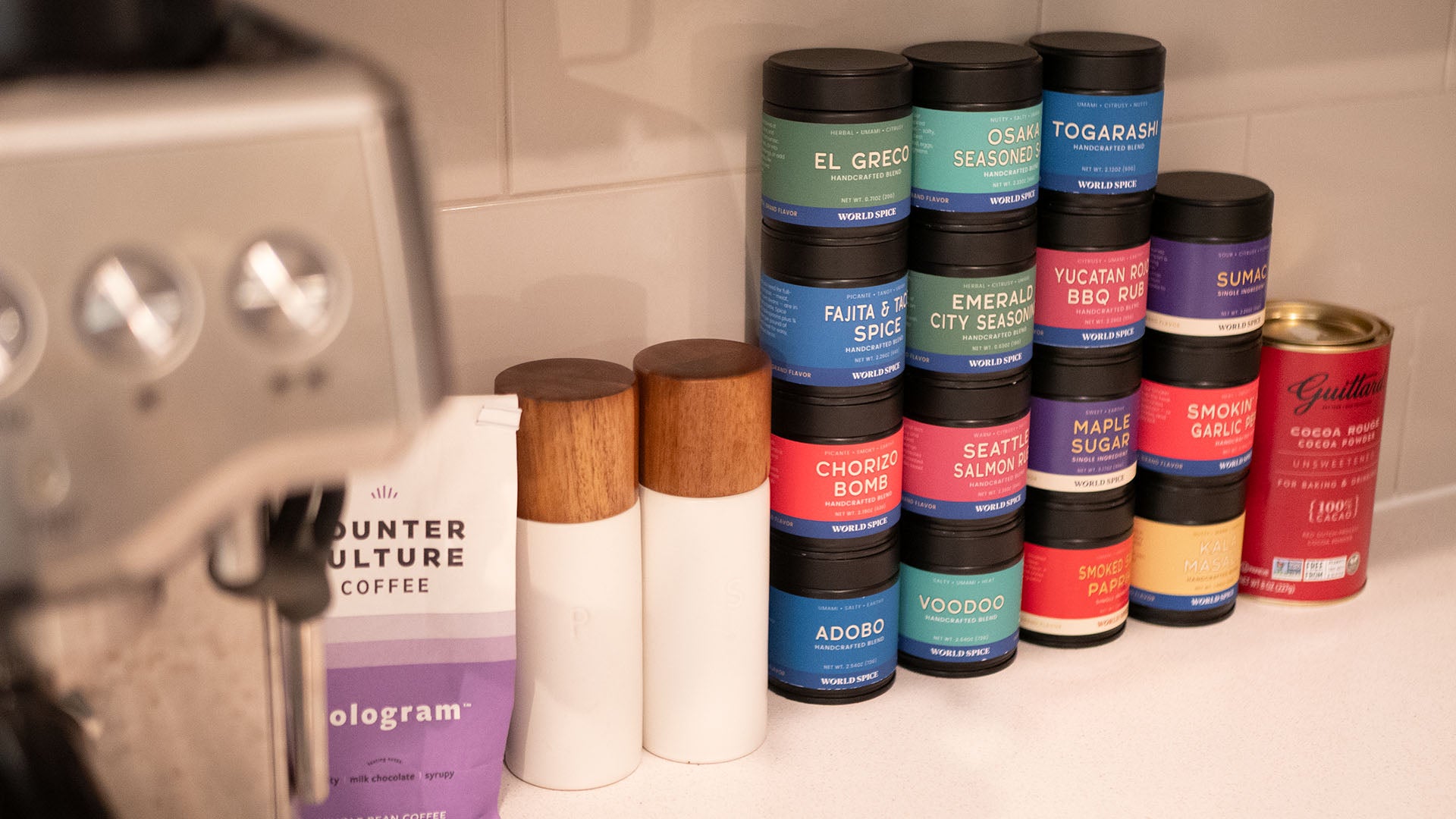 Stack of various spice containers on a kitchen counter with a blurred background