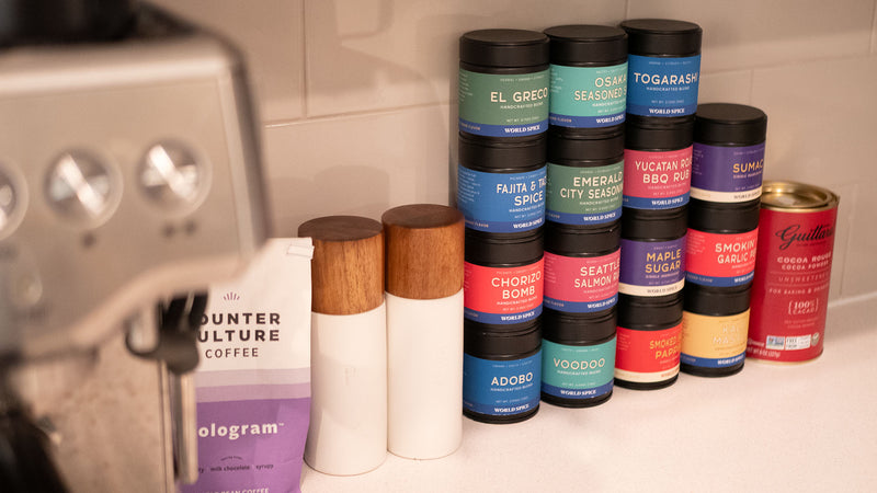 Stack of various spice containers on a kitchen counter with a blurred background